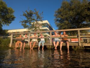Sechs Sänger*innen genießen das Chorwochenenden mit den Füßen im See